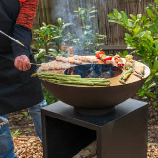 Sfeerfoto koken met een vuurschaal plancha met houtopslag