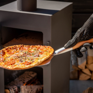 BBQ Handschoen die een persoon aan heeft om een pizza in de oven te doen met een pizzaschep